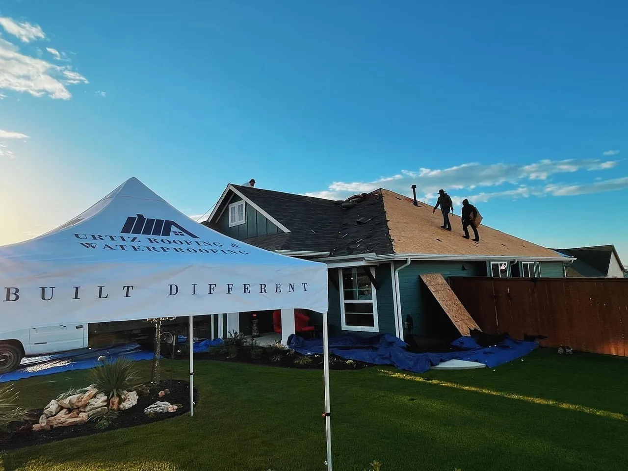 Urtiz Roofing crew at active job site with branded tent reading Built Different
